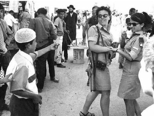 一名巴勒斯坦少年向以色列国防军的女兵赠送纪念品。耶路撒冷，1967年。