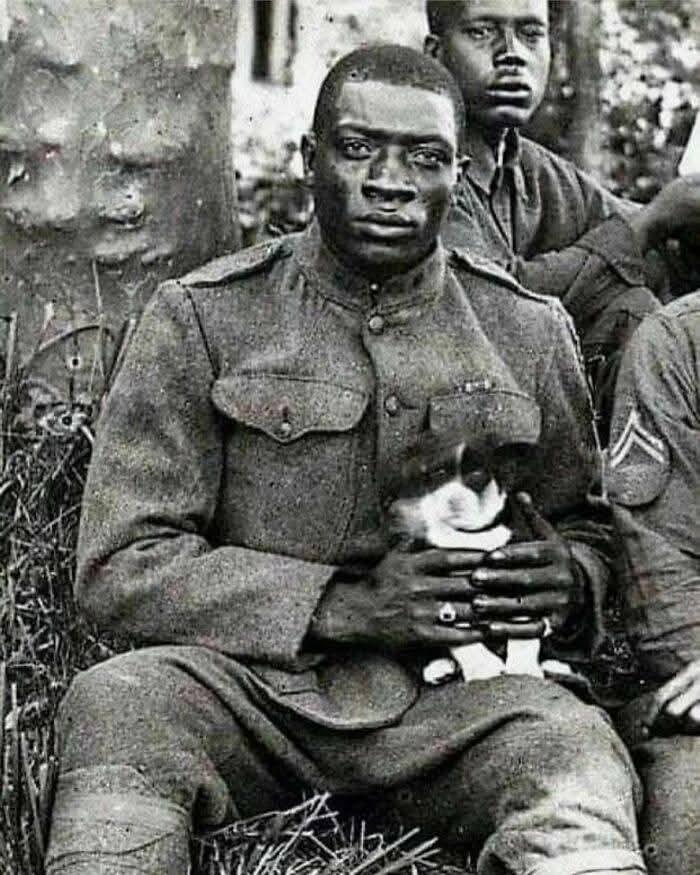 一名哈莱姆地狱战士（第369步兵团）成员在1918年第一次世界大战期间抱着一只他救下的小狗，面对镜头合影。