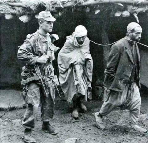 法国殖民士兵用铁链拖拽着两名阿尔及利亚男子——这是阿尔及利亚殖民历史中一段黑暗的记忆。