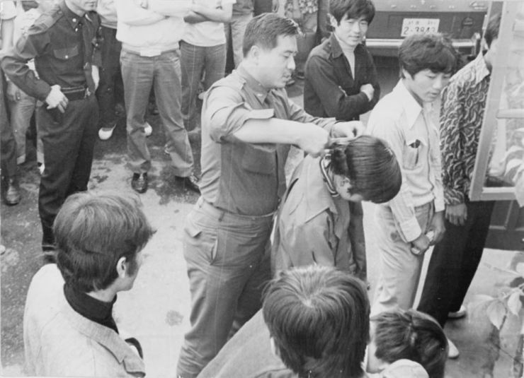 一名韩国士兵在众人面前强行剪掉一名年轻人的头发